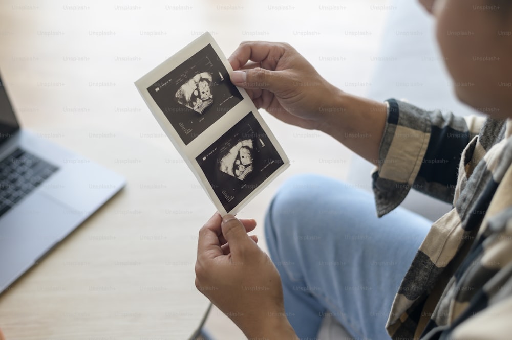 Padre joven sosteniendo la foto del ultrasonido del bebé recién nacido, la maternidad y el concepto de la familia