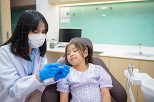 Uma dentista feminina mostrando invisalign para uma garotinha na clínica odontológica, check-up de dentes e conceito de dentes saudáveis