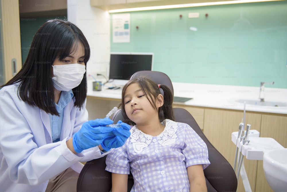 Eine Zahnärztin, die einem kleinen Mädchen in der Zahnklinik invisalign zeigt, Zahnkontrolle und Konzept für gesunde Zähne