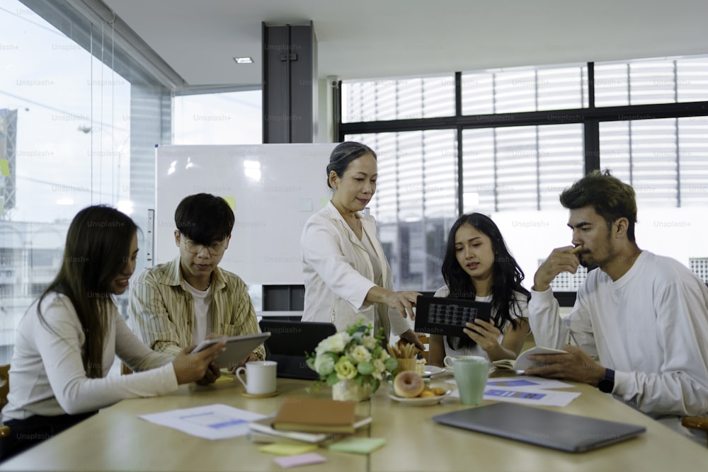 Treffen asiatischer Geschäftsleute, die sich der Arbeit verschrieben haben. Kreatives Business-Team sitzt zusammen im Büro.