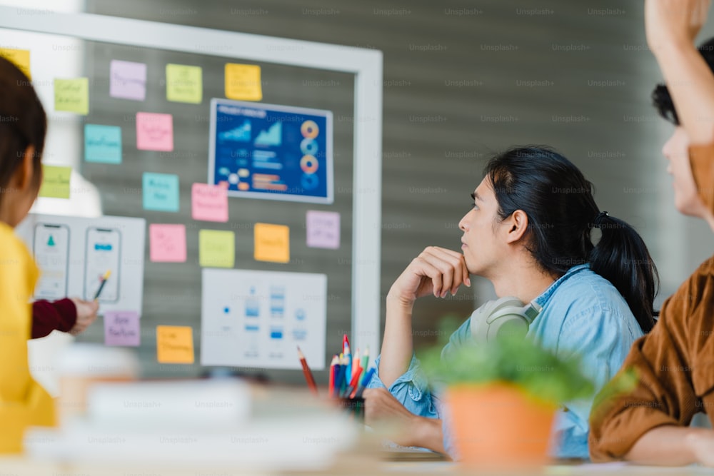 Grupo de jóvenes creativos de Asia que se re�únen para la lluvia de ideas, la realización de ideas para presentaciones de negocios, el diseño de software de aplicaciones móviles, los colegas del proyecto en la oficina moderna. Concepto de trabajo en equipo de compañeros de trabajo