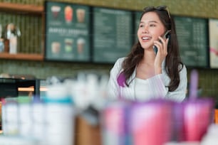 魅力的なスマートカジュアルアジアの女性の手入力チャットスマートフォンテレコミュニケーションを使用してチャットカフェで前向きな姿勢の笑顔カジュアル、カフェでスマートフォンを操作するスマートビジネスオーナー起業家