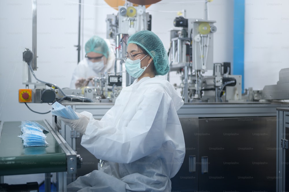 Trabajadores que producen mascarillas quirúrgicas en fábricas modernas, protección Covid-19 y concepto médico.