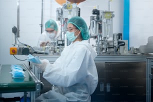 Workers producing surgical mask in modern factory, Covid-19 protection and medical concept.