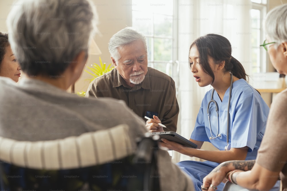 happiness Cheerful elderly woman and men talking with female caregiver nurse doctor having health checking consult at living area,Caretakers with senior couple sitting in living room at nursing home