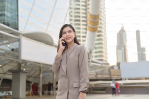 A young beautiful businesswoman is using Smart phone in Modern city , business technology , city lifestyle concept