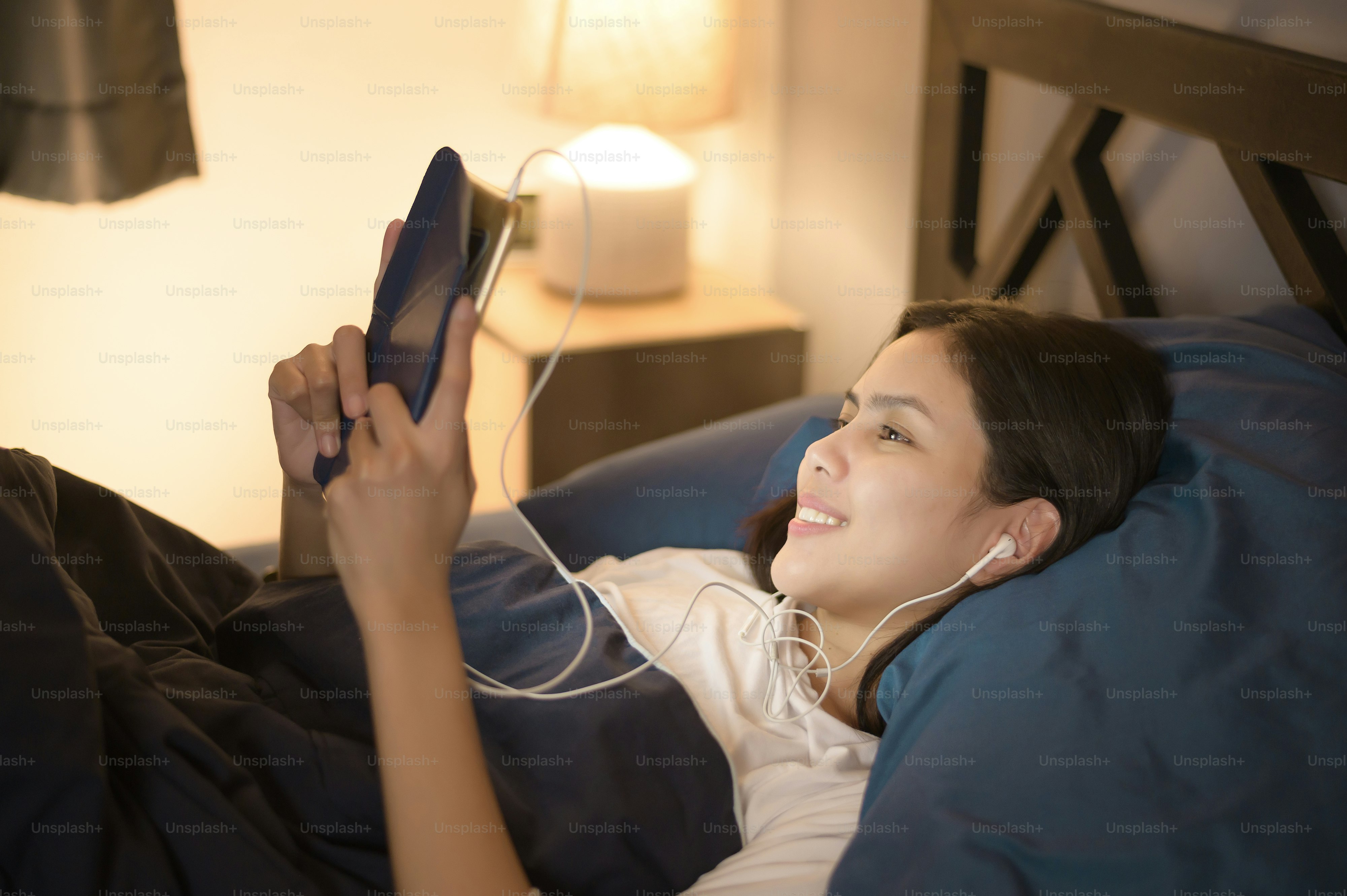 A young woman is using tablet , watching movies or video call to her friends or family in her bedroom , night Light