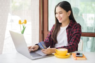 Beautiful woman is online shopping with credit card in coffee shop