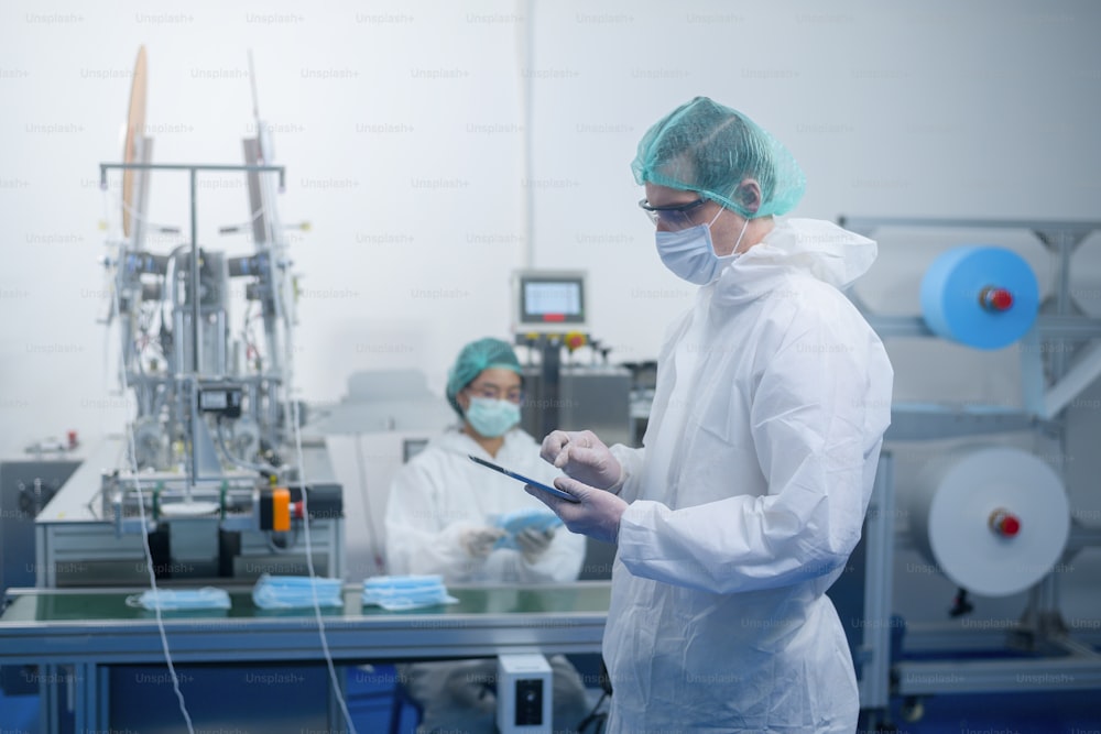 현대 공장에서 수술용 마스크를 생산하는 근로자, Covid-19 보호 및 의료 개념.
