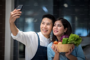 Portrait of couple man and woman taking selfie photo while cooking in kitchen at home