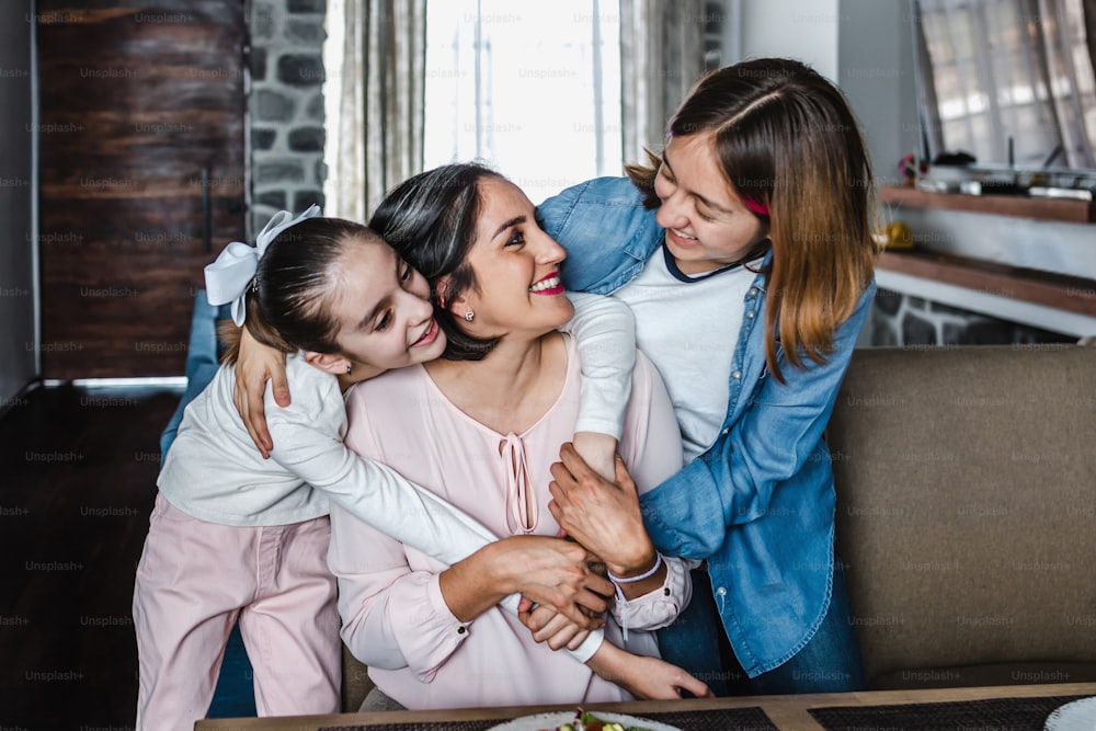 hispanic Mother hugging her daughters at cozy living room at home in Mexico Latin America. Family time
