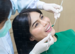 Mujer joven que tiene dientes examinados por el dentista en la clínica dental, chequeo de los dientes y concepto de dientes sanos