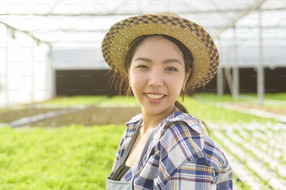 Una joven agricultora que trabaja en una granja de invernadero hidropónico, alimentos limpios y concepto de alimentación saludable