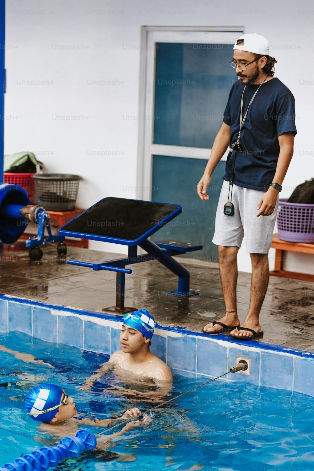 Entrenador de nadadores latinos hablando algunos consejos a adolescentes nadadores estudiantes en la piscina en México América Latina