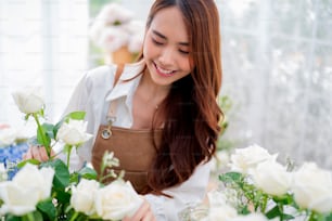 Small business. Asia Female florist smile arranging flowers in floral shop. Flower design store. happiness smiling young lady making flower vase for customers, preparing flower work from home business