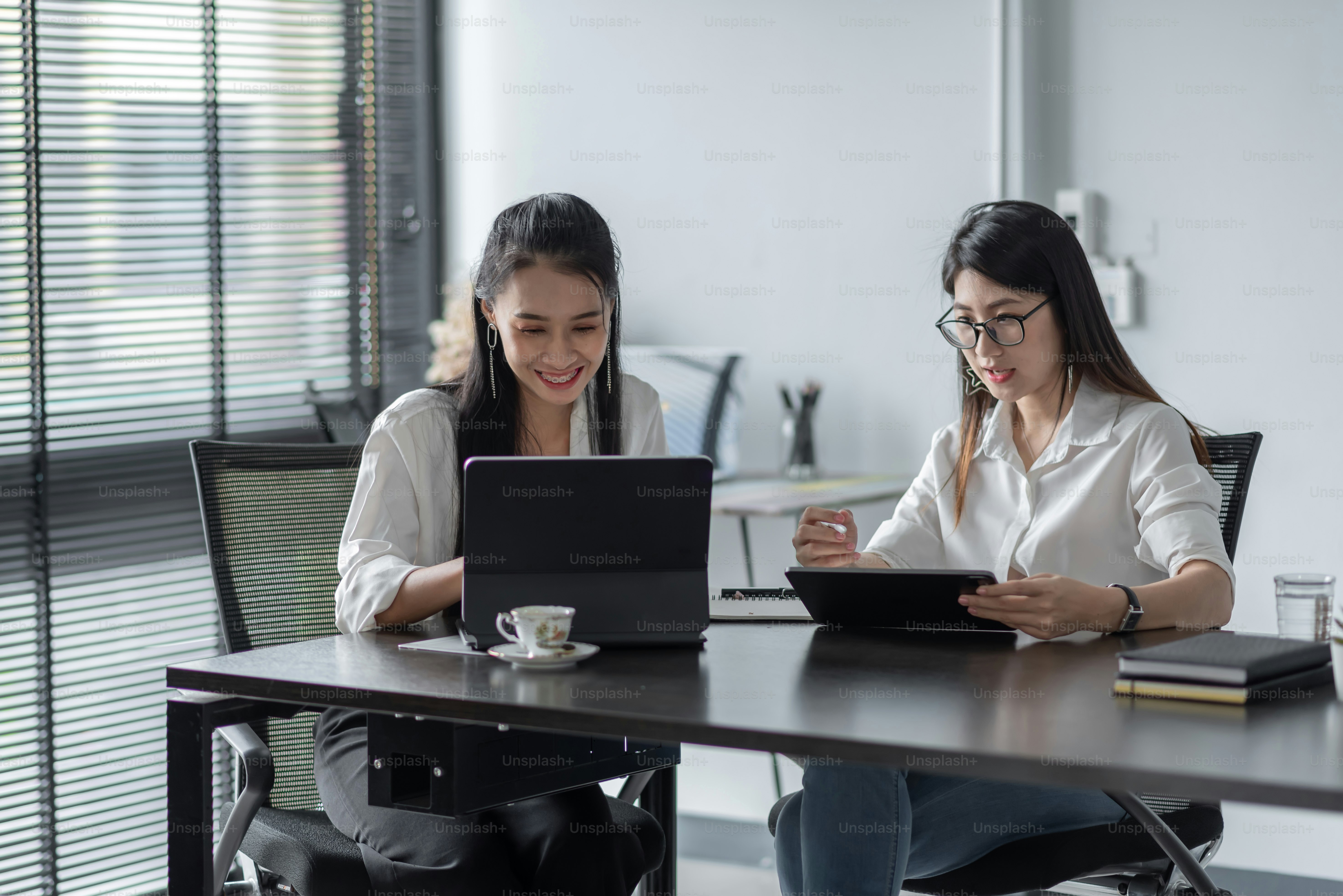 Deux jeunes femmes d’affaires asiatiques sont heureuses de travailler ...