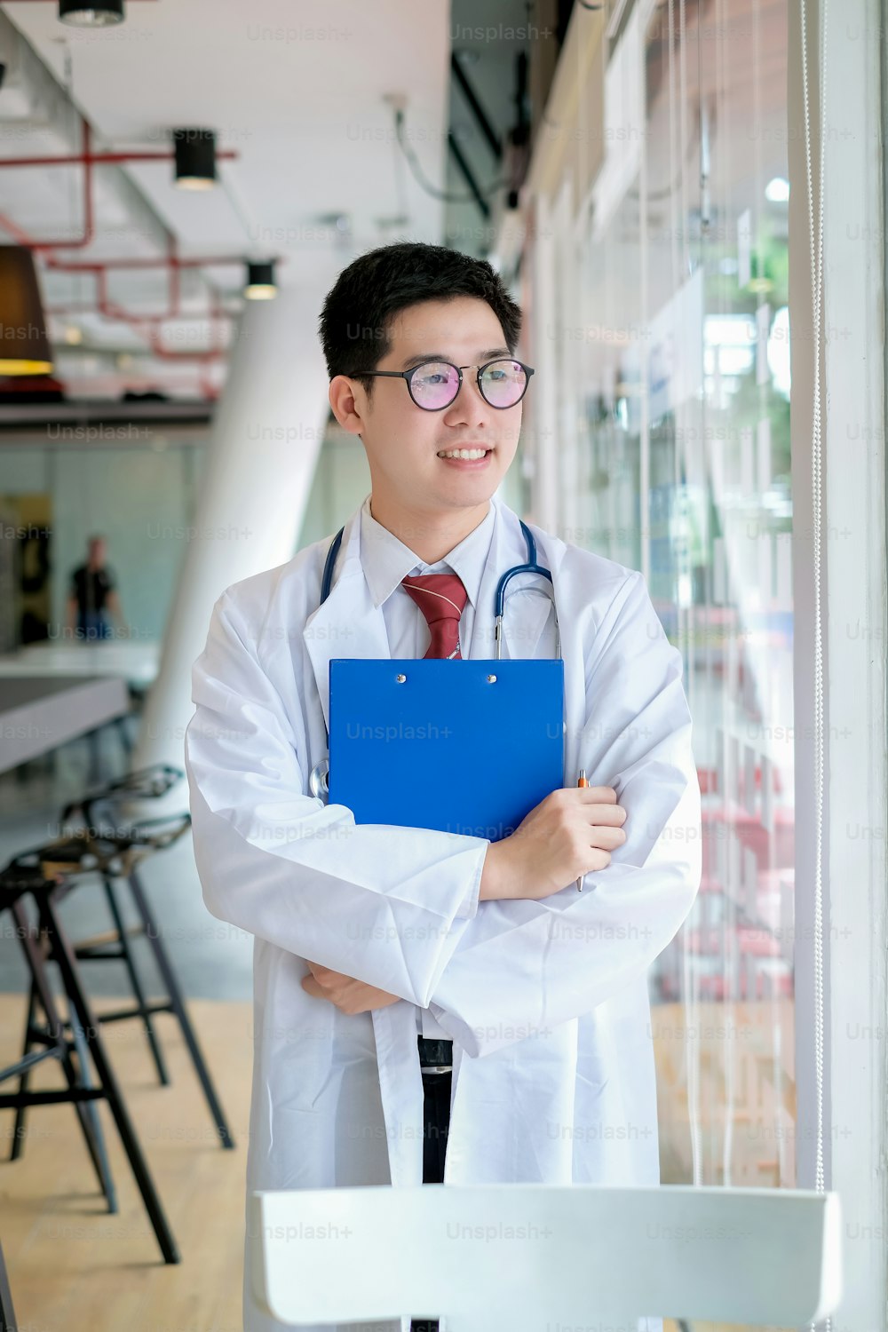 Male doctor stand holding the clipboard in his office.
