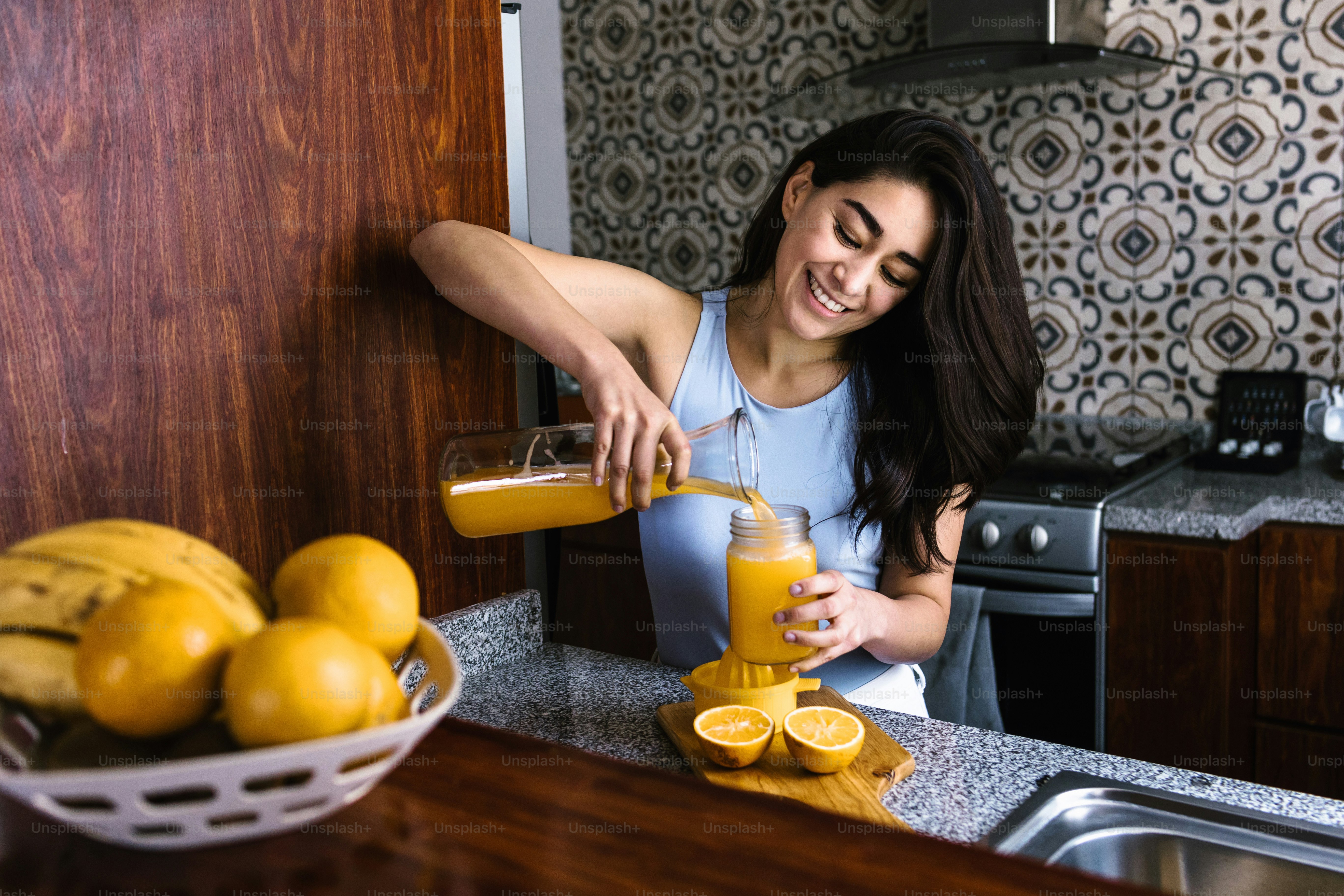 Hispanic young latin woman preparing orange juice at the