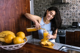 Hispanic brunette young latin woman preparing orange juice at the kitchen in Mexico Latin America