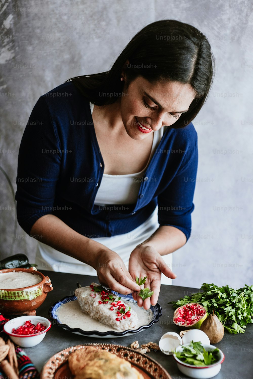 mujer mexicana cocinando receta de chiles en nogada con chile poblano e ingredientes, plato tradicional en Puebla México