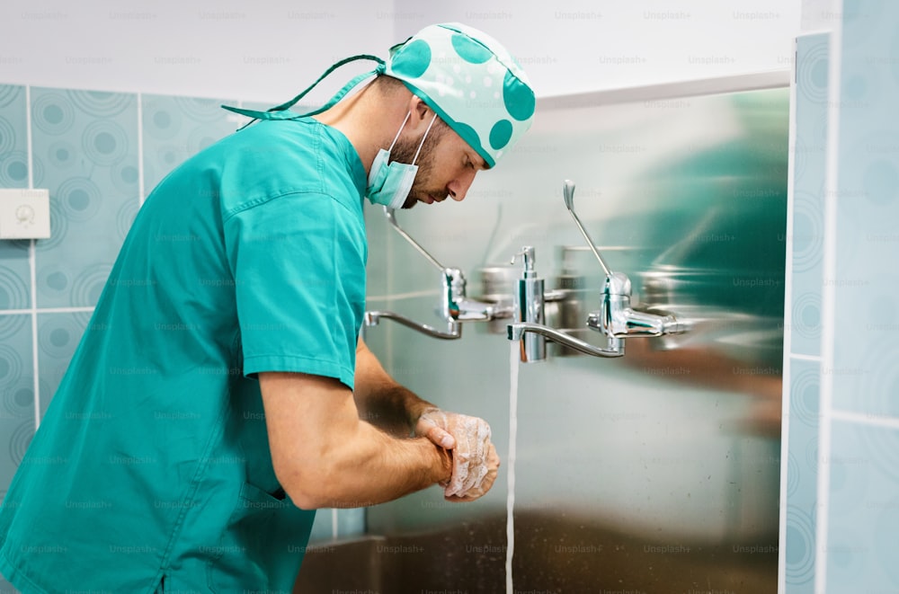 Chirurgo che lava le mani all'operazione utilizzando la tecnica corretta per la pulizia in ospedale