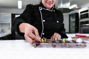 hand of latin woman pastry chef wearing black uniform in process of preparing delicious sweets chocolates at kitchen in Mexico Latin America