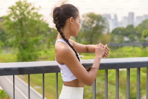 A young fitness woman in sportswear using smart watch while exercising in city park, Healthy and Lifestyles.