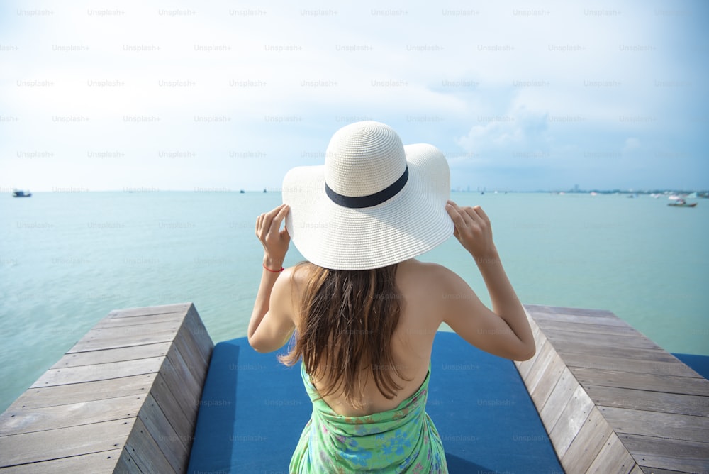 Rücken einer Frau mit weißem Hut am Strand