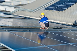 Técnico asiático que instala paneles de células solares de inspección o reparación en el campo de fondo de los paneles solares fotovoltaicos, células solares en la fábrica de tejados.