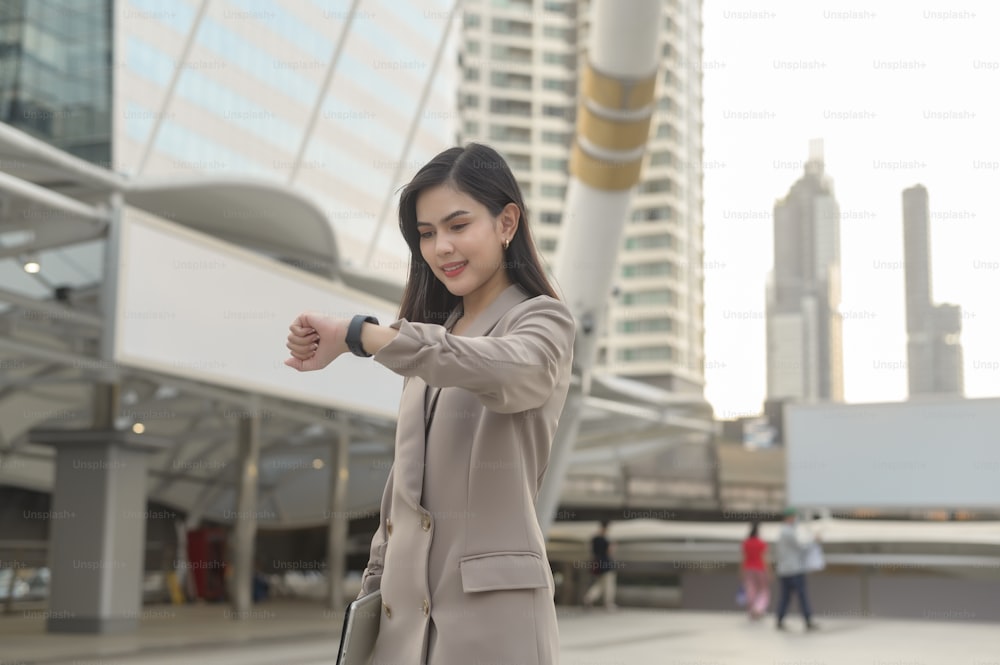 Empresária está usando relógio inteligente na cidade moderna, tecnologia de negócios, conceito de estilo de vida da cidade