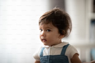 Cute little toddler girl holding circular cookie toy while sitting on floor with stuff toy in living room playing with young father at home