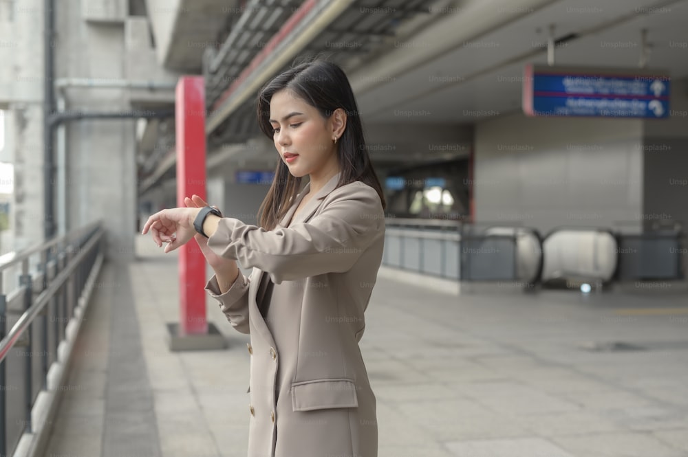 L'imprenditrice sta usando l'orologio intelligente nella città moderna, nella tecnologia aziendale, nel concetto di stile di vita della città