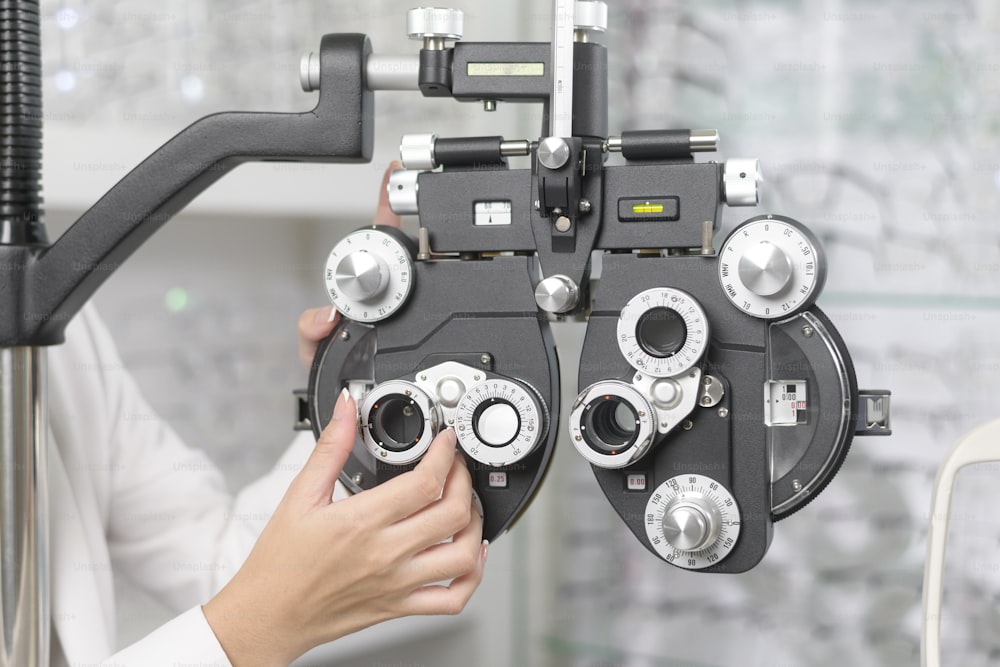 Jovem oftalmologista fazendo teste visual para cliente utilizando dispositivo de medição de visão de Optometria Bifocal em centro óptico, conceito de cuidados com os olhos.