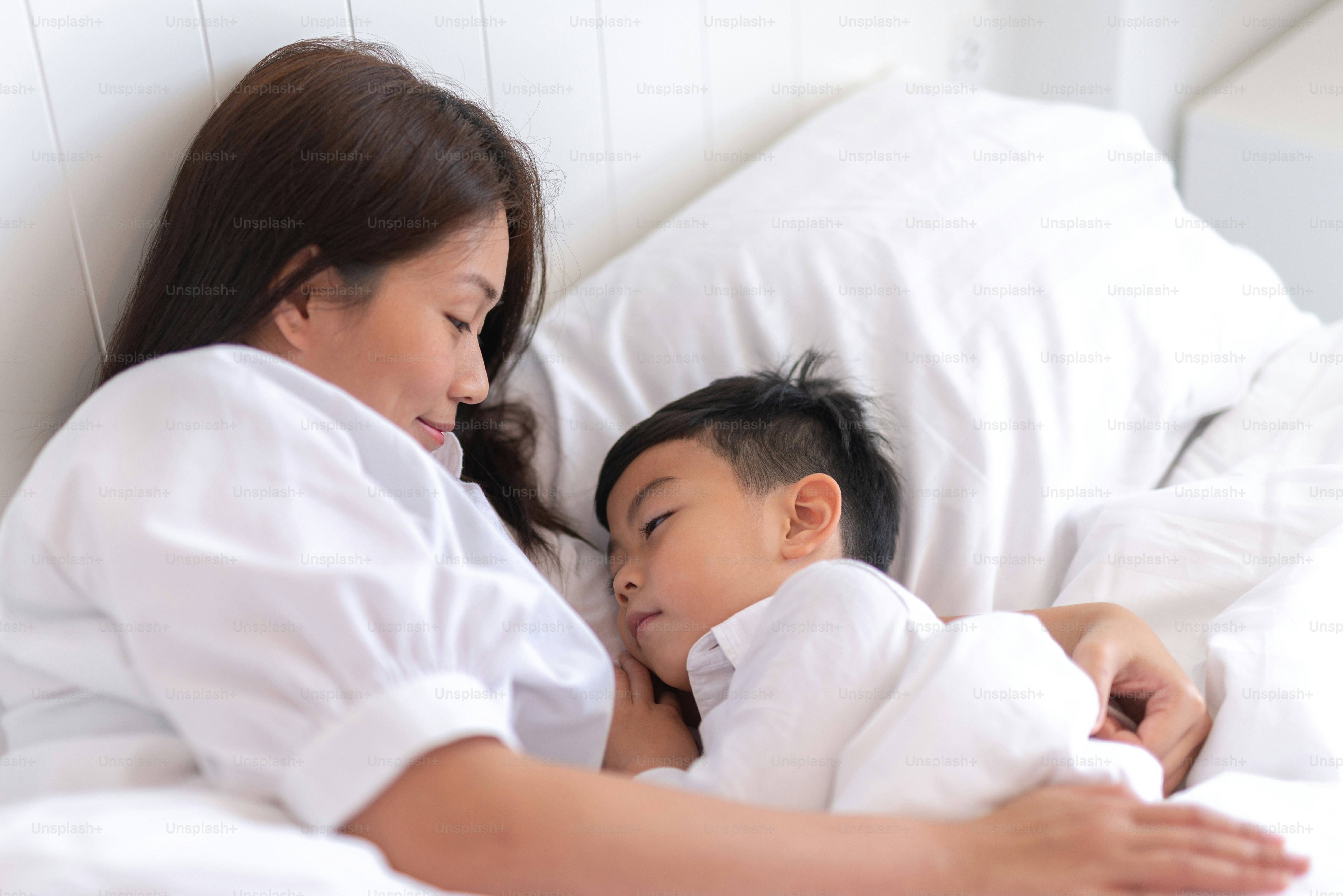 Foto Madre feliz y sonriente acostada en la cama con su hijo ...