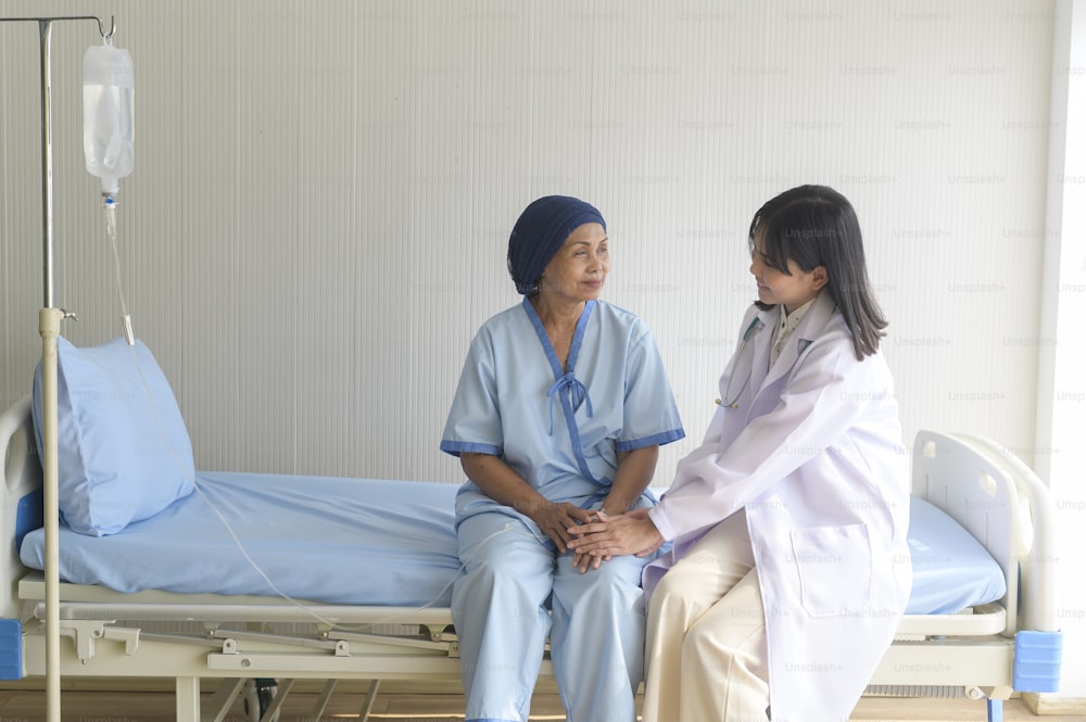 Doctor holding senior cancer patient's hand in hospital, health care and medical concept