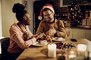 Glückliches Paar, das das Weihnachtsessen genießt und Händchen haltend am Esstisch zu Hause ist.