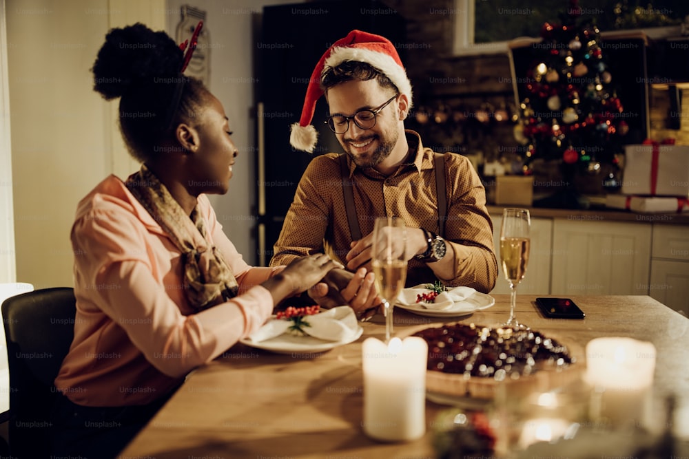 Heureux couple profitant du dîner de Noël et se tenant la main à la table à manger à la maison.