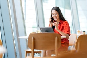 Détendez-vous loisirs attrayant intelligent asiatique femme freelance entrepreneur sourire et profiter de travailler avec smartphone et ordinateur portable au café avec flou ville entreprise nomade numérique casual idées concept