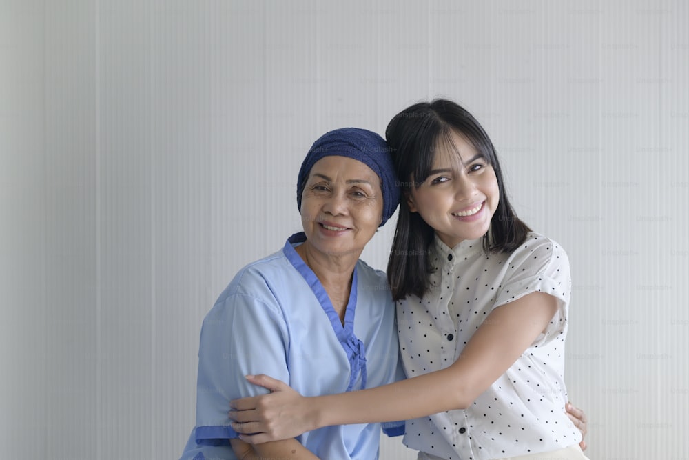 Mulher paciente com câncer usando lenço na cabeça e sua filha de apoio no hospital, saúde e conceito de seguro.