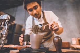 Barista profesional que hace una bebida caliente de un café fresco en una cafetería vintage, una taza de espresso caliente con aroma marrón, cafeína de bebida para la mañana, grano de café y fondo de desayuno