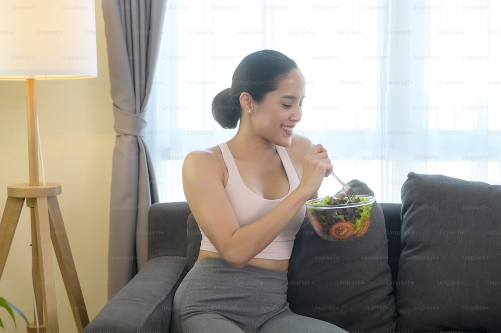 Fit young woman having salad after work out at home, sport and healthy lifestyle concept.