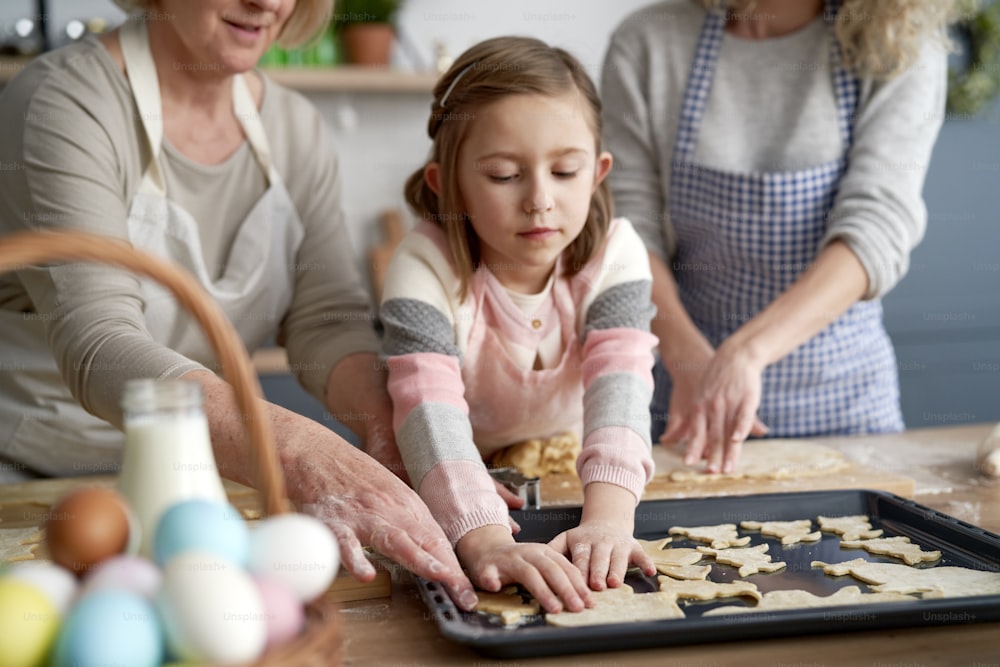 Little girl making Easter cookies with family