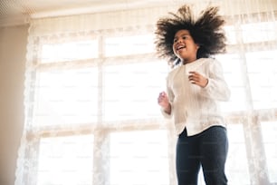 a little boy jumping on the bed, brother and sister sibling playing together, afro young boy in white background, cozy time at home. family relationship concept.