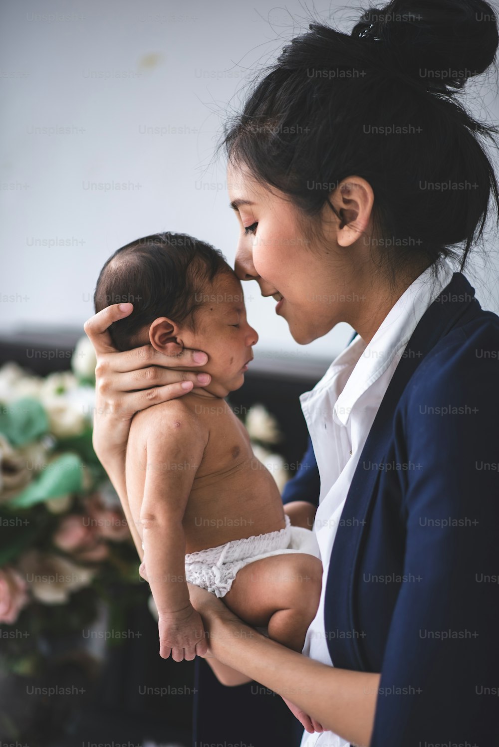 Businesswoman working from home, holding baby girl