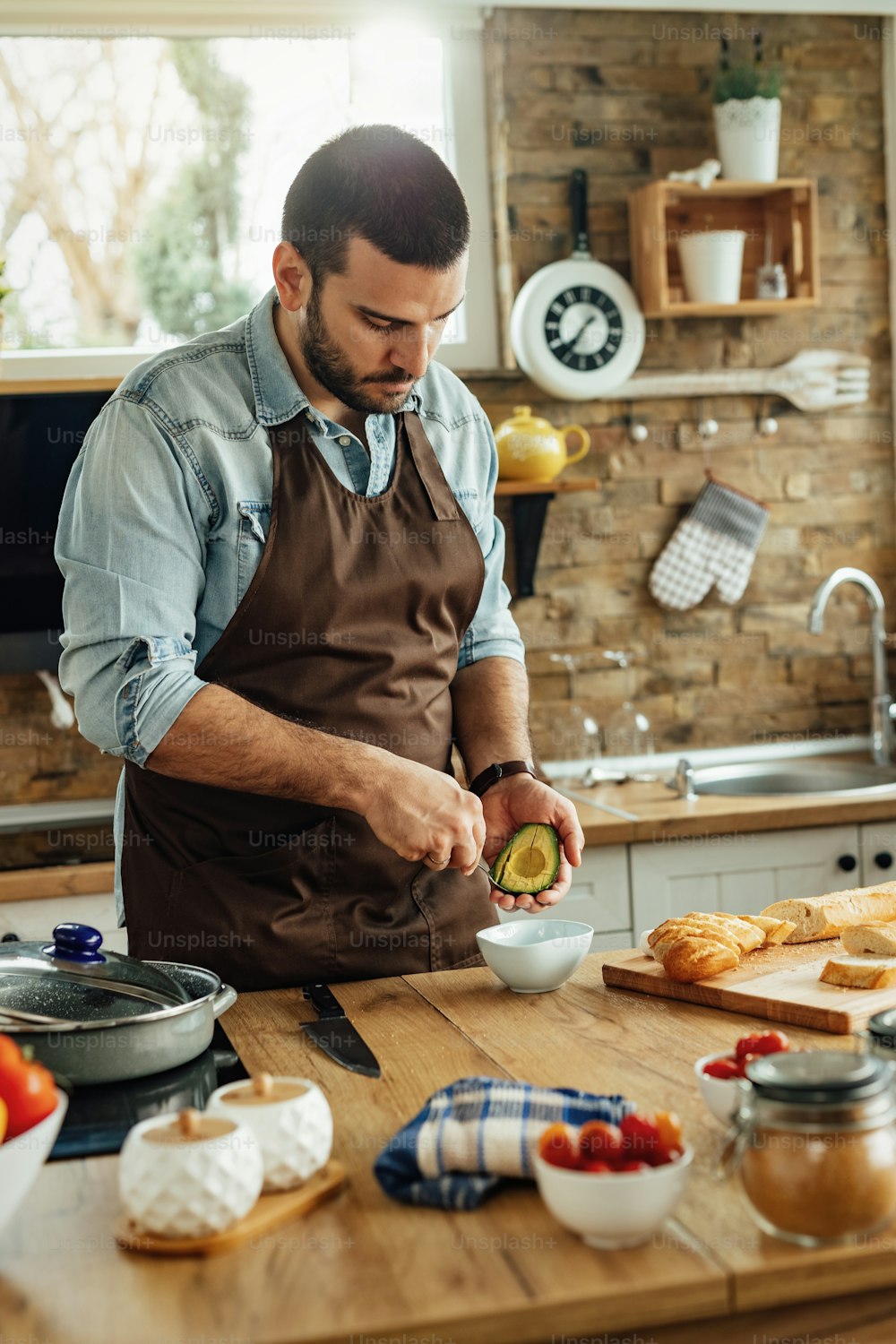 Young man using avocado while preparing healthy meal in the kitchen.