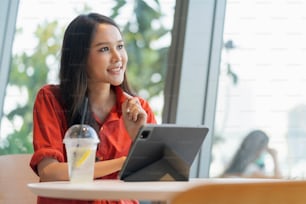 Entspannen Sie sich in der Freizeit Attraktiv Attraktiv Asiatische Freiberuflerin Lächeln und genießen Sie die Arbeit mit Smartphone und Laptop im Café mit Blur City Business Digital Nomad Casual Ideas Konzept