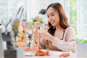 Asian Female spend weekend day for her hobby clay scuplture online course at home, young adult making study from tablet streaming course online in apron costume,asian casual lifestyle at home