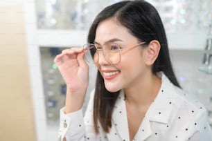 A young female customer choosing glasses in optical center, Eyecare concept.