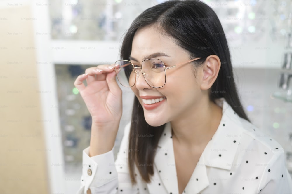 Una joven clienta que elige gafas en el centro óptico, concepto de cuidado de los ojos.
