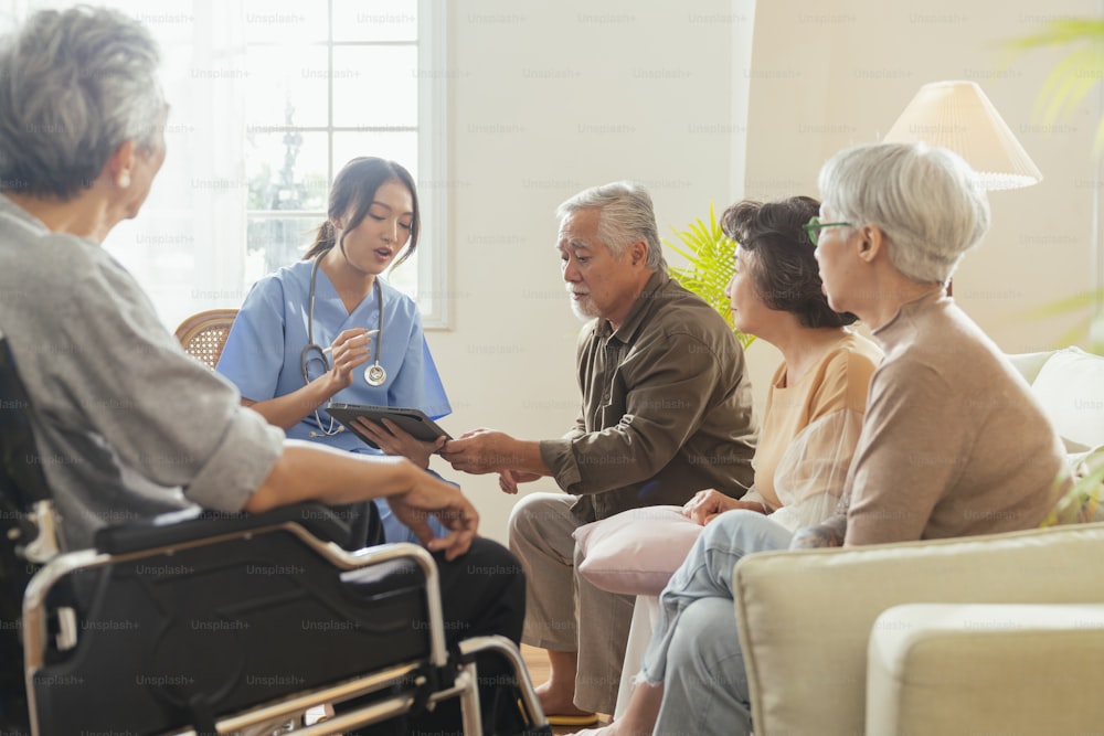 happiness Cheerful elderly woman and men talking with female caregiver nurse doctor having health checking consult at living area,Caretakers with senior couple sitting in living room at nursing home